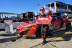 Race car driver in black suit holding MOTUL Pole Award banner next to red NSX GT3 Evo race car.