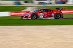 Red and black race car number 93 speeding on race track with sponsor logos and blurred background.
