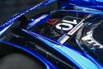 Close-up of blue race car body with number 10 and sponsor decals on sleek aerodynamic surface.