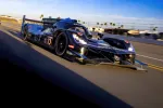 Black Acura race car number 10 speeding on a racetrack with clear blue sky and palm trees in background