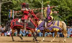 Two knights in red and purple armor jousting on horseback during a medieval reenactment event.