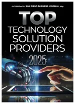 Human hand and robotic hand nearly touching above a digital tablet, symbolizing top technology solutions of 2025.