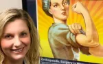 Smiling woman stands next to a strong Rosie the Riveter poster symbolizing empowerment and resilience.