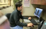 Man analyzing medical images on a computer screen in a clinical office setting.
