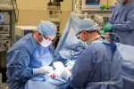 Surgeons in blue scrubs and masks performing a precise operation in a well-equipped surgical room.