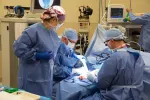 Surgeons and medical staff perform operation in sterile operating room with advanced medical equipment.