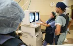 Medical professionals reviewing diagnostic images on monitors in a hospital examination room.