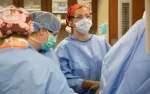Medical team in surgical gowns and masks performing an operation in a hospital operating room.