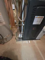 AC Inspection in Atlanta by The Air Company of GA.  Basement furnace and water heater installation showing pipes, insulation, and control labels on units.