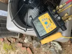 AC Repair and Maintenance in Alpharetta 30005 by The Air Company of GA. Close-up of HVAC digital manifold gauge measuring pressure and temperature on an outdoor air conditioning unit.
