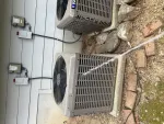 AC Repair and Maintenance in Alpharetta 30005 by The Air Company of GA. Two outdoor HVAC units installed on concrete pads beside a house with visible wiring and surrounding rocks and bricks.