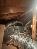 AC Repair in Peachtree Corners by The Air Company of GA. HVAC system with insulated flexible ducts installed in a wooden attic space and supporting pipes.