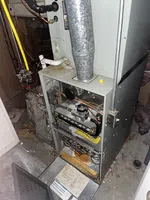 Atlanta Buckhead Air Conditioning Repair by The Air Company of GA. Open gas furnace showing internal wiring, gas valve, and exhaust pipe in a basement setting.