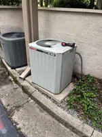 Atlanta Buckhead Air Conditioning Repair by The Air Company of GA. Outdoor Trane XE 1000 air conditioning unit by a wall with a flashlight on top, next to another similar unit.