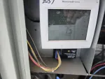 Commercial HVAC Repair in Alpharetta by The Air Company of GA. Honeywell Home thermostat showing indoor temperature of 75 degrees installed inside HVAC unit with visible wiring.