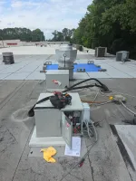 Atlanta Commercial Refrigeration Repair and Cleaning by The Air Company of GA. HVAC unit on commercial rooftop with tools and open panel under maintenance on cloudy day.
