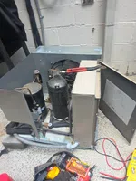 Commercial Walk-In Cooler Repair in Sandy Springs by The Air Company of GA. Open HVAC unit with visible compressor and coils, surrounded by repair tools including pliers and multimeter.