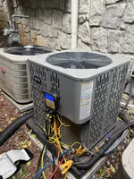 AC inspection in Atlanta by The Air Company of GA. Two outdoor air conditioning units with diagnostic tools and colorful hoses attached near a stone wall.