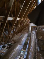 Commercial HVAC Duct Repair in Marietta 30066 by The Air Company of GA.  Attic space with wooden beams, insulation, and large silver HVAC ductwork running along the floor of the attic.