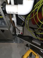 AC Cooling Repair in Atlanta 30318 by The Air Company. Furnace system with PVC pipes, drainage pump, electrical cords, and yellow extension cords on concrete floor.