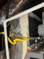 Heating Furnace Repair in Alpharetta 30009 by The Air Company of GA.  Close-up of HVAC system ductwork with insulation, wiring, and a yellow flexible gas line in a basement ceiling.
