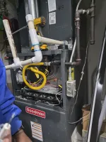 Commercial HVAC Repair in Dunwoody 30338 by The Air Company of GA.  Open Goodman furnace showing internal components, pipes, yellow wiring, and a cordless drill on top.