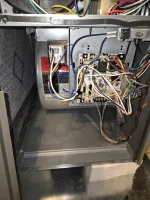 Open HVAC system showing wiring, circuit board, and fan assembly inside a metal casing with multi-colored wires.