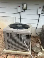 AC Repair and Maintenance in Alpharetta 30005 by The Air Company of GA. Two outdoor HVAC units installed on concrete pads beside a house with visible wiring and surrounding rocks and bricks.