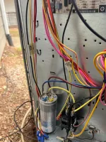 Residential Heating Furnace HVAC Repair in Dunwoody 30338 by The Air Company of GA.  Close-up of colorful electrical wires connected to a metal panel with a capacitor and relay outdoors.