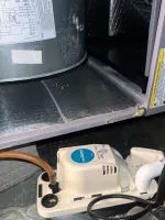 Residential Heating Furnace HVAC Repair in Dunwoody 30338 by The Air Company of GA.  Close-up of a Uni-GIANT condensate pump installed next to HVAC ductwork with connected pipes and wires.