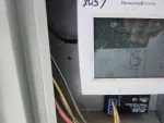 Commercial HVAC Repair in Alpharetta by The Air Company of GA. Honeywell Home thermostat showing indoor temperature of 75 degrees installed inside HVAC unit with visible wiring.