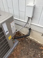 AC Heating Unit Installation in Atlanta 30306 by The Air Company of GA. Outdoor air conditioning unit with electrical conduit and insulated refrigerant lines against white siding and dirt ground.