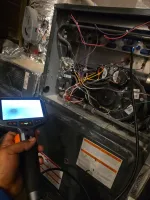 Residential AC Cooling Repair in Atlanta 30327 by The Air Company of GA.  Hand holding inspection camera in front of an open HVAC furnace with wires and components exposed.