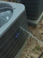 AC Repair and Maintenance in Smyrna 30080 by The Air Company of GA. Outdoor Carrier air conditioning unit being sprayed with water on dirt ground with leaves.