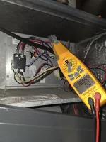 AC Heat Repair in Atlanta 30309 by The Air Company of GA.  Yellow clamp meter measuring voltage and current inside an electrical panel with multiple wires and components.