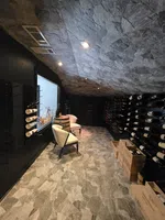 Wine Cellar Installation in Atlanta by The Air Company of GA.  Cozy wine cellar with stone floor, sloped stone ceiling, wine racks, two chairs, and wooden barrel table.