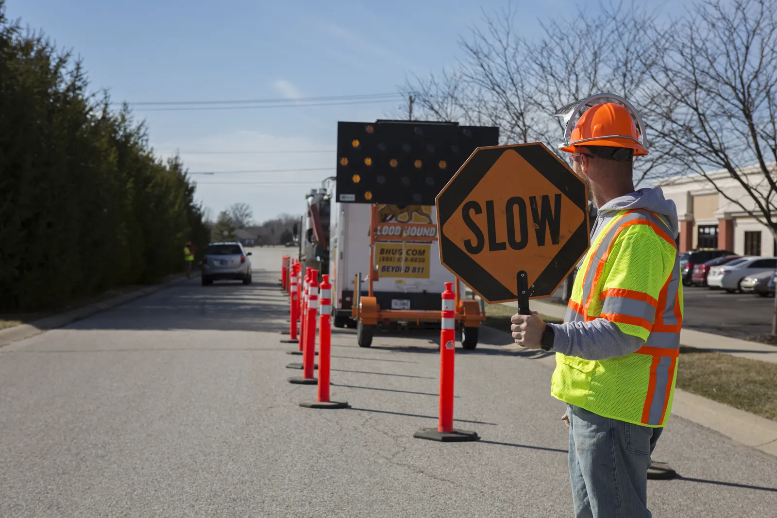 Man in construction gear holding a slow sign to manage traffic safety