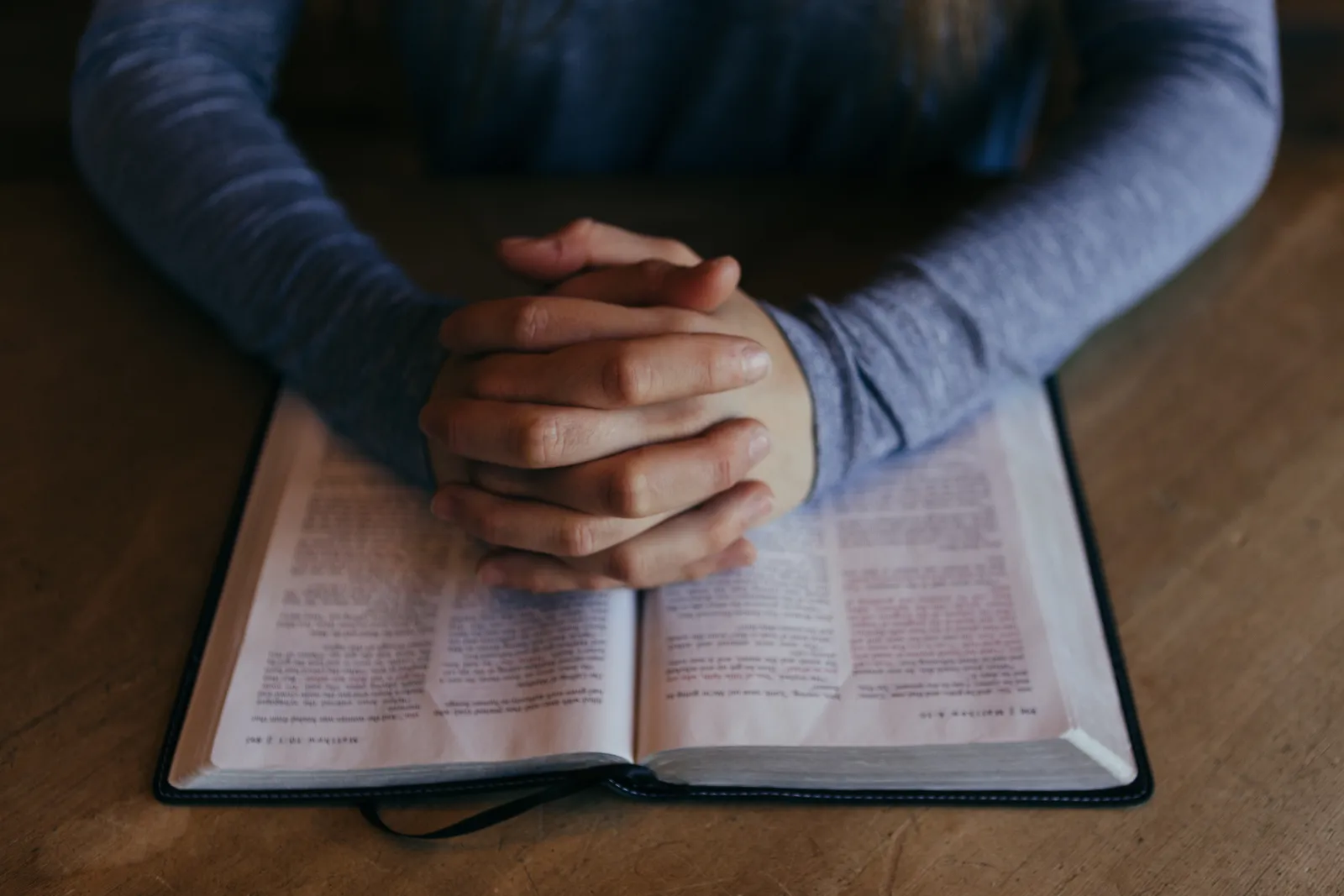 Open bible with hands together on top