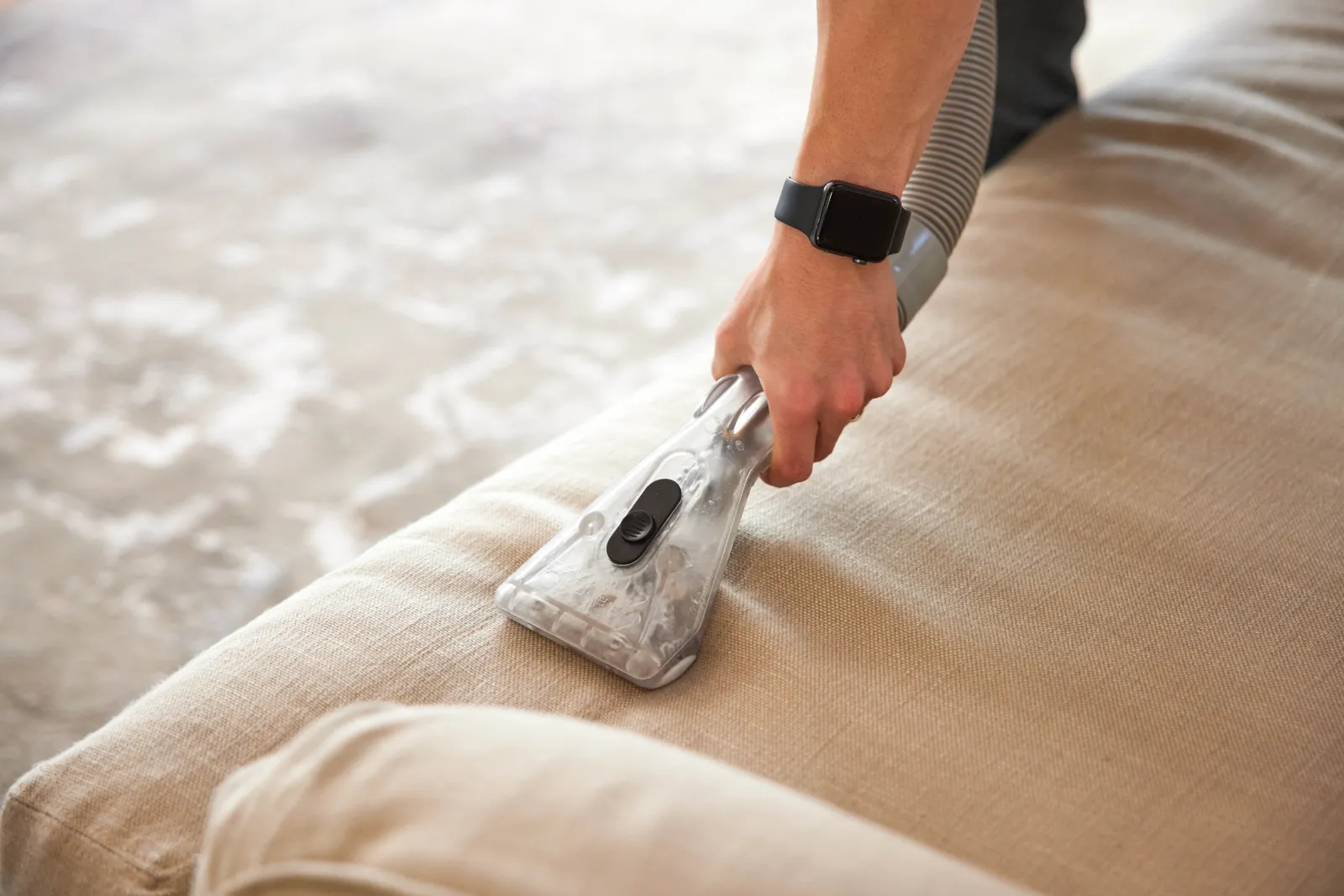 person operates a vacuum cleaner on a couch, effectively cleaning its fabric surface