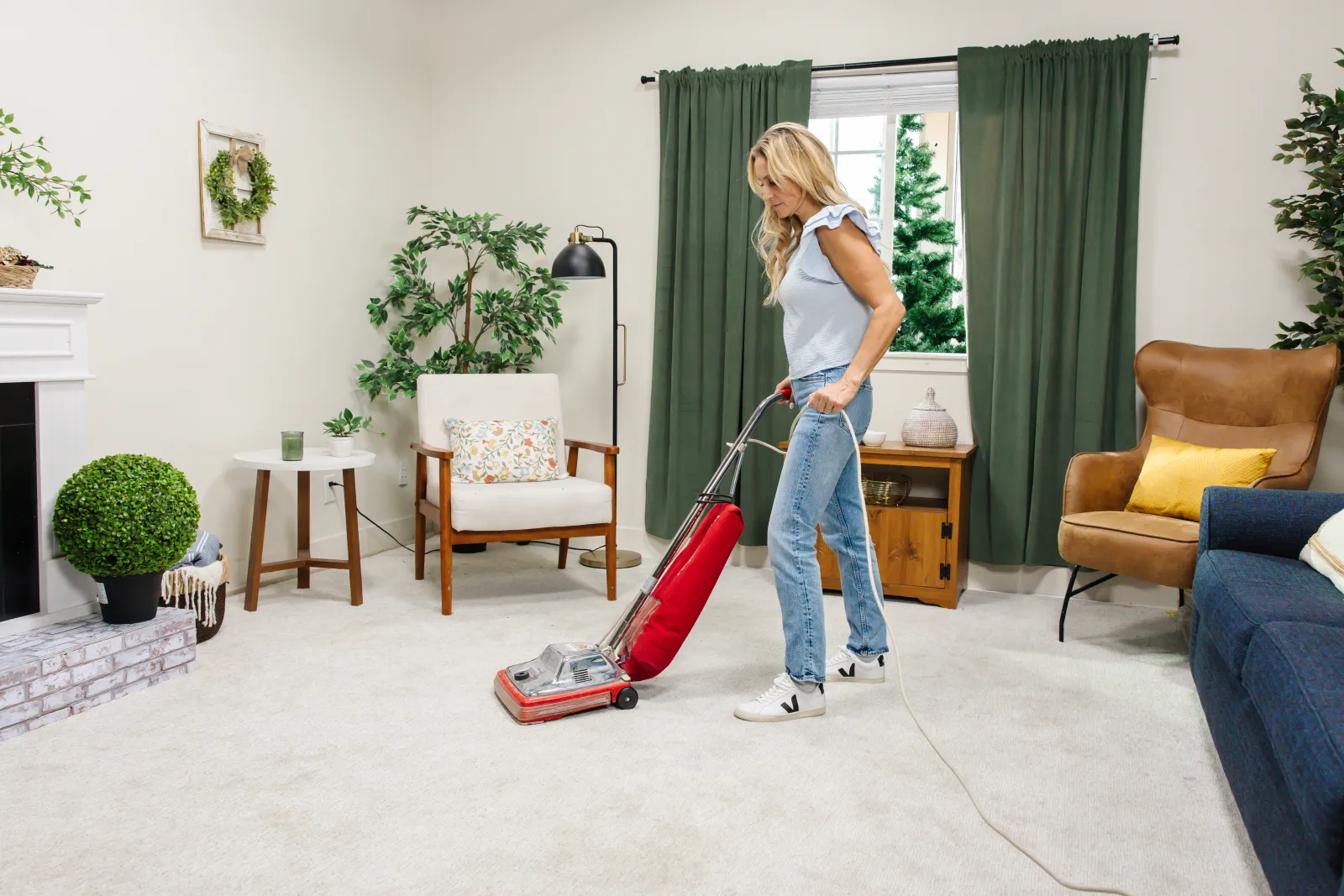 a woman vacuuming the carpet in a cozy living room filled with furniture and decor