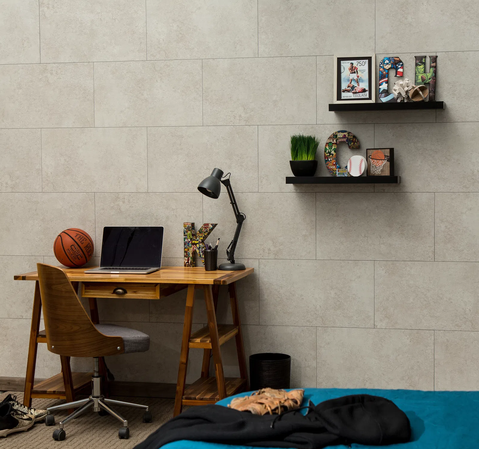 Modern bedroom workspace with wooden desk, basketball, laptop, decorative letters, and shelves with sports-themed decor.