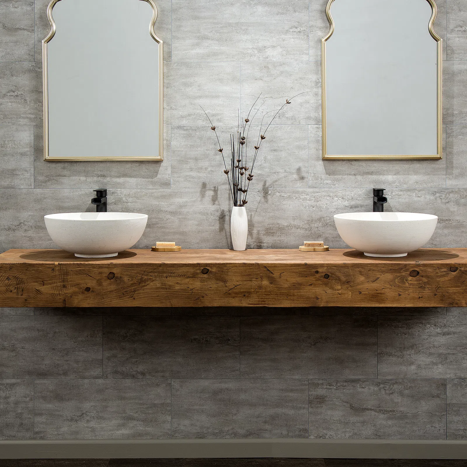 Modern double bathroom vanity with white vessel sinks, wooden countertop, decorative vase, and stylish mirrors.