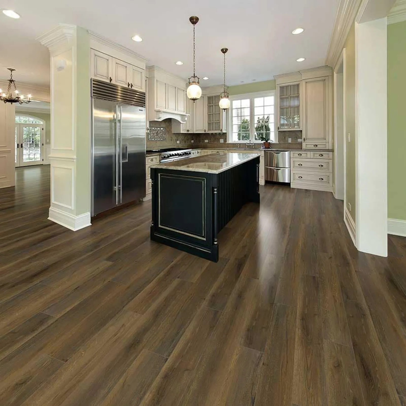 Modern kitchen with dark wood flooring, black island, white cabinets, stainless steel appliances, and pendant lights.