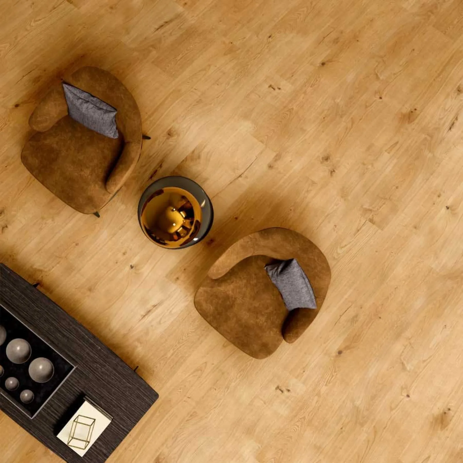 Top view of two brown armchairs with gray pillows around a round glass table on wooden floor