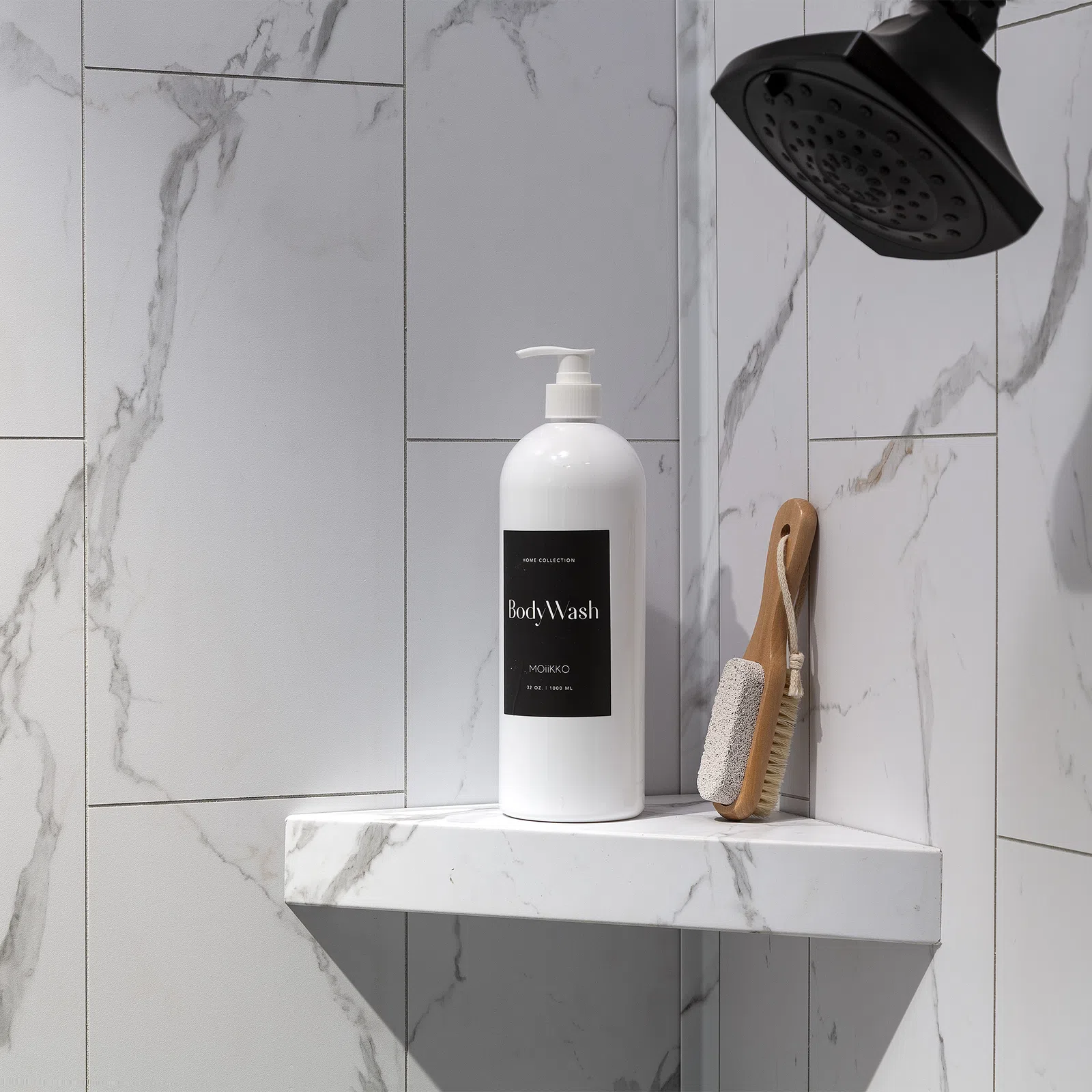 White body wash bottle and wooden brush on marble shower shelf under black showerhead in modern bathroom