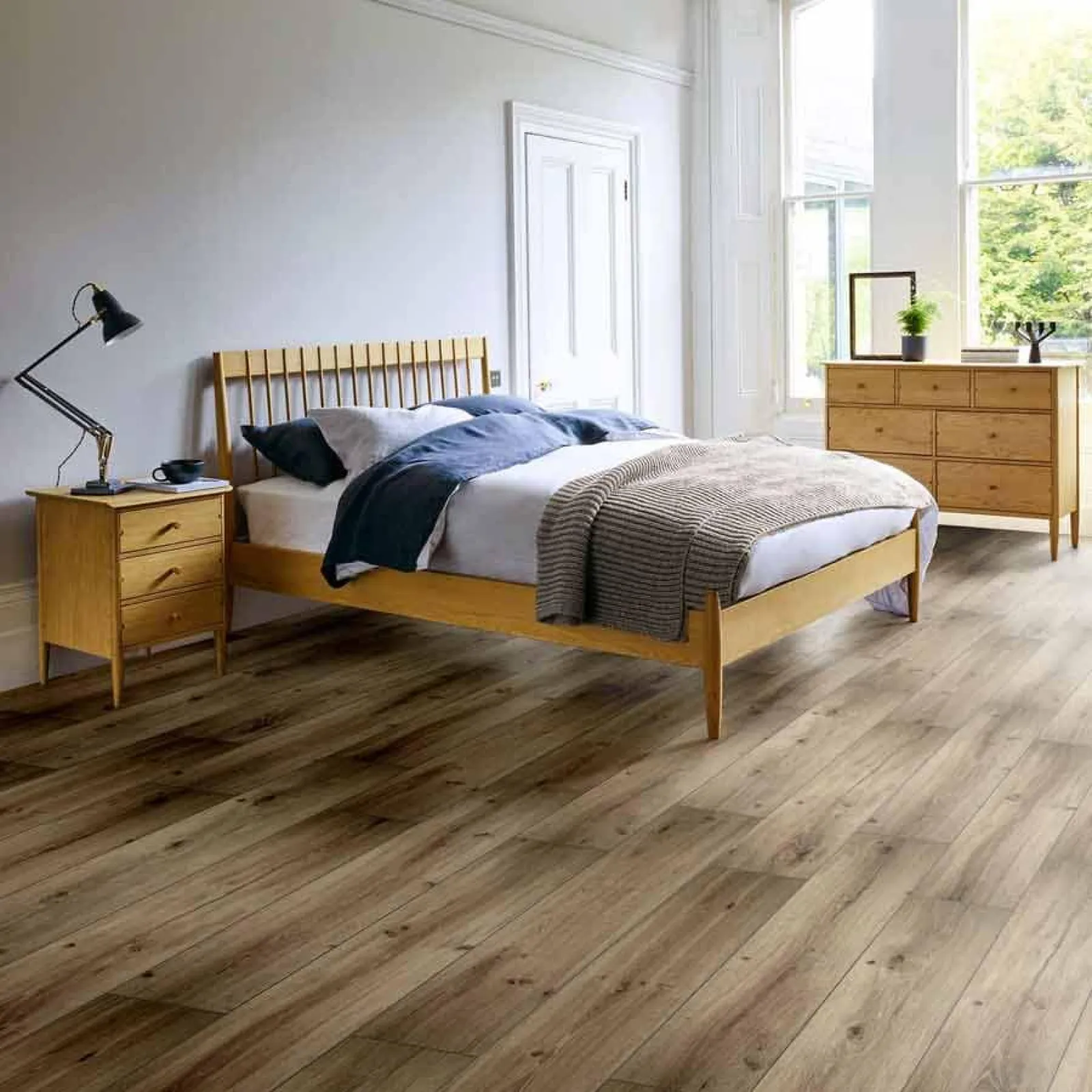 Modern bedroom with wooden bed frame, hardwood floor, dresser, nightstand, and natural light from large windows.