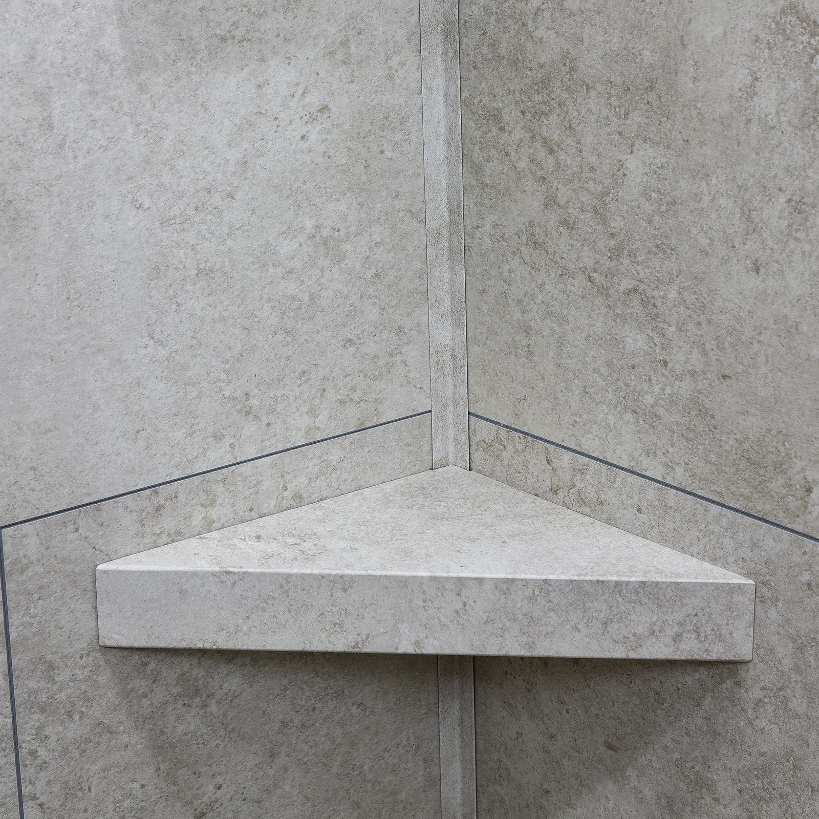 Triangular stone corner shelf mounted on beige tiled wall with subtle texture and grout lines
