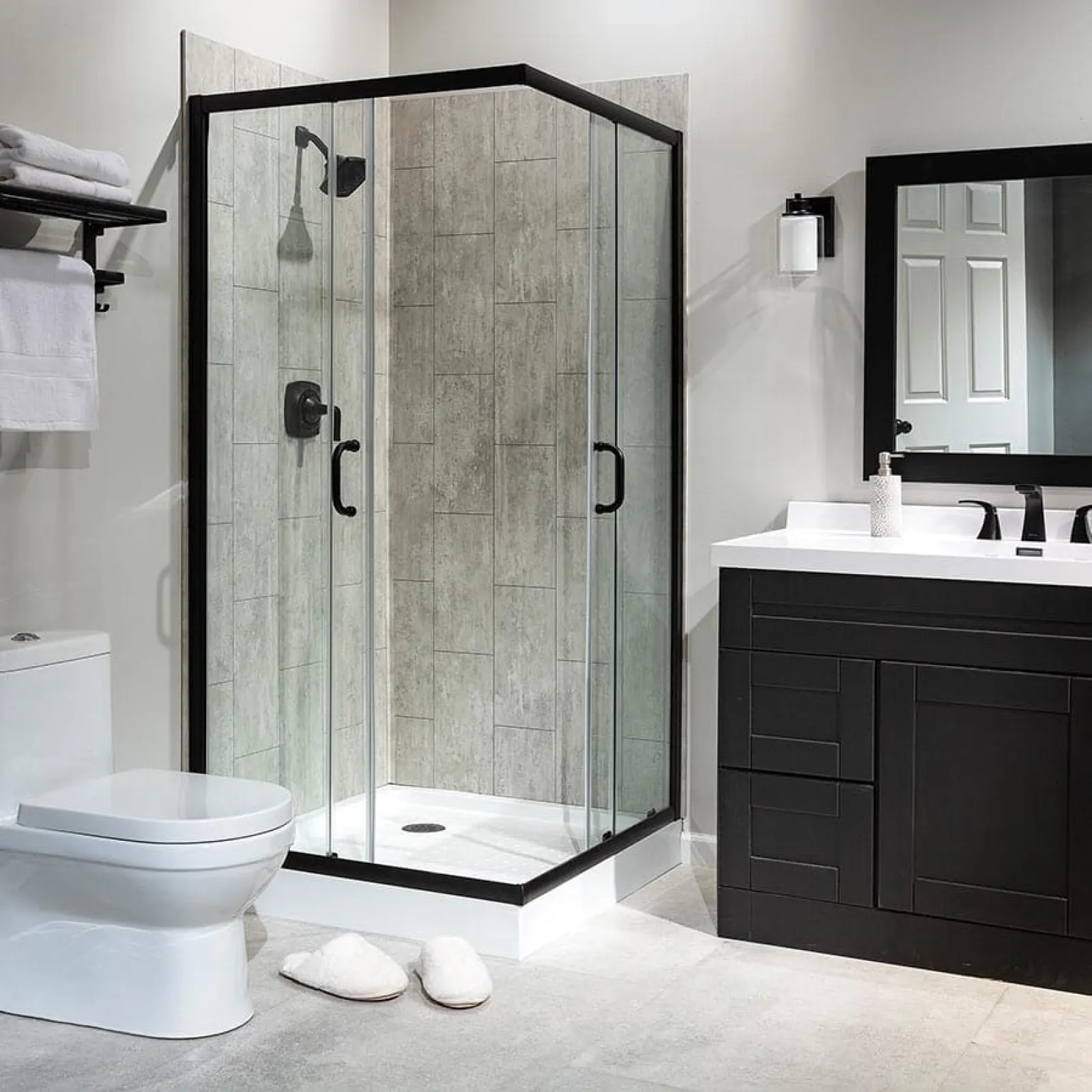 Modern bathroom with glass shower enclosure, black vanity, toilet, and neutral tile flooring and walls.