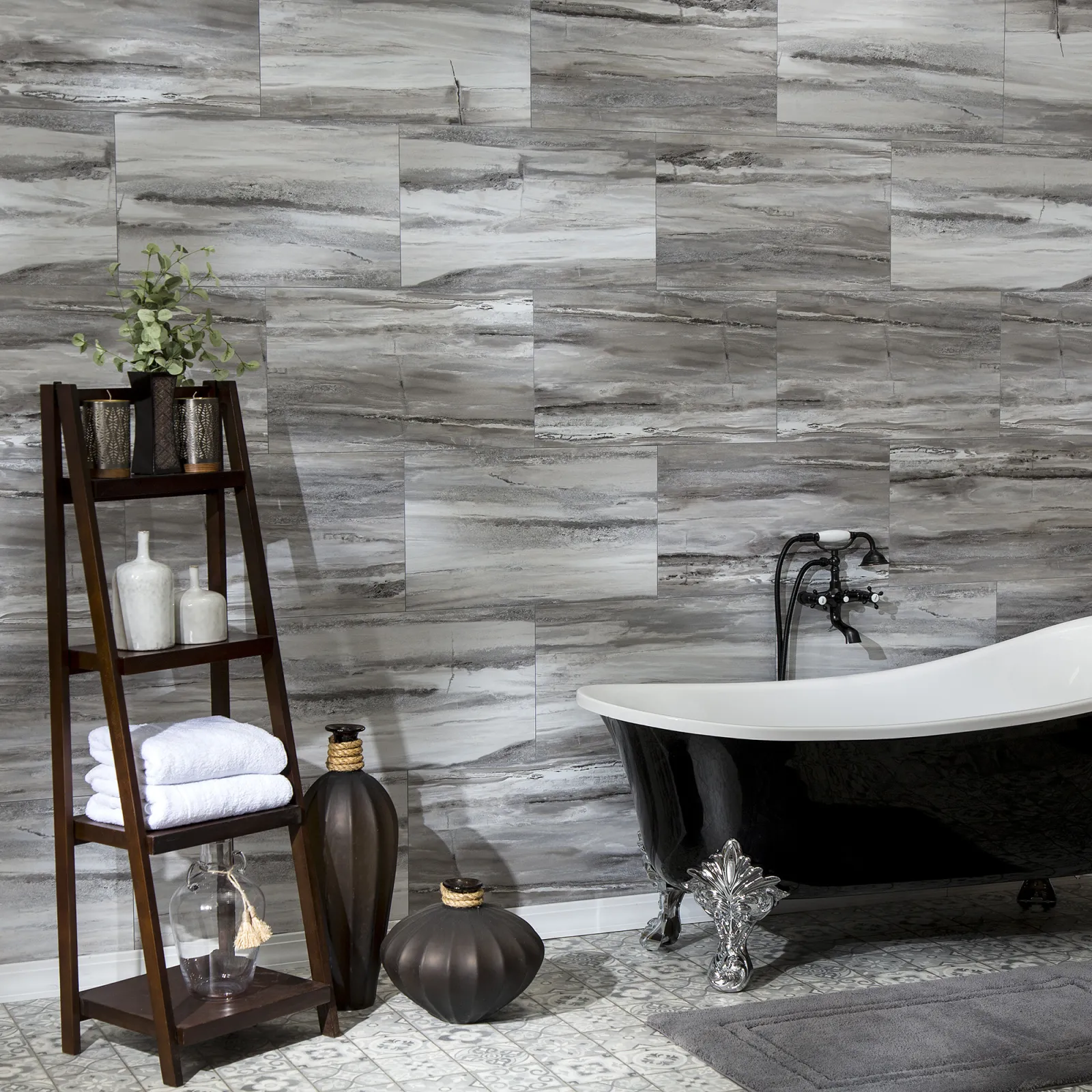 Modern bathroom with a black clawfoot tub, wood shelf holding towels and decor, and gray marble wall tiles.