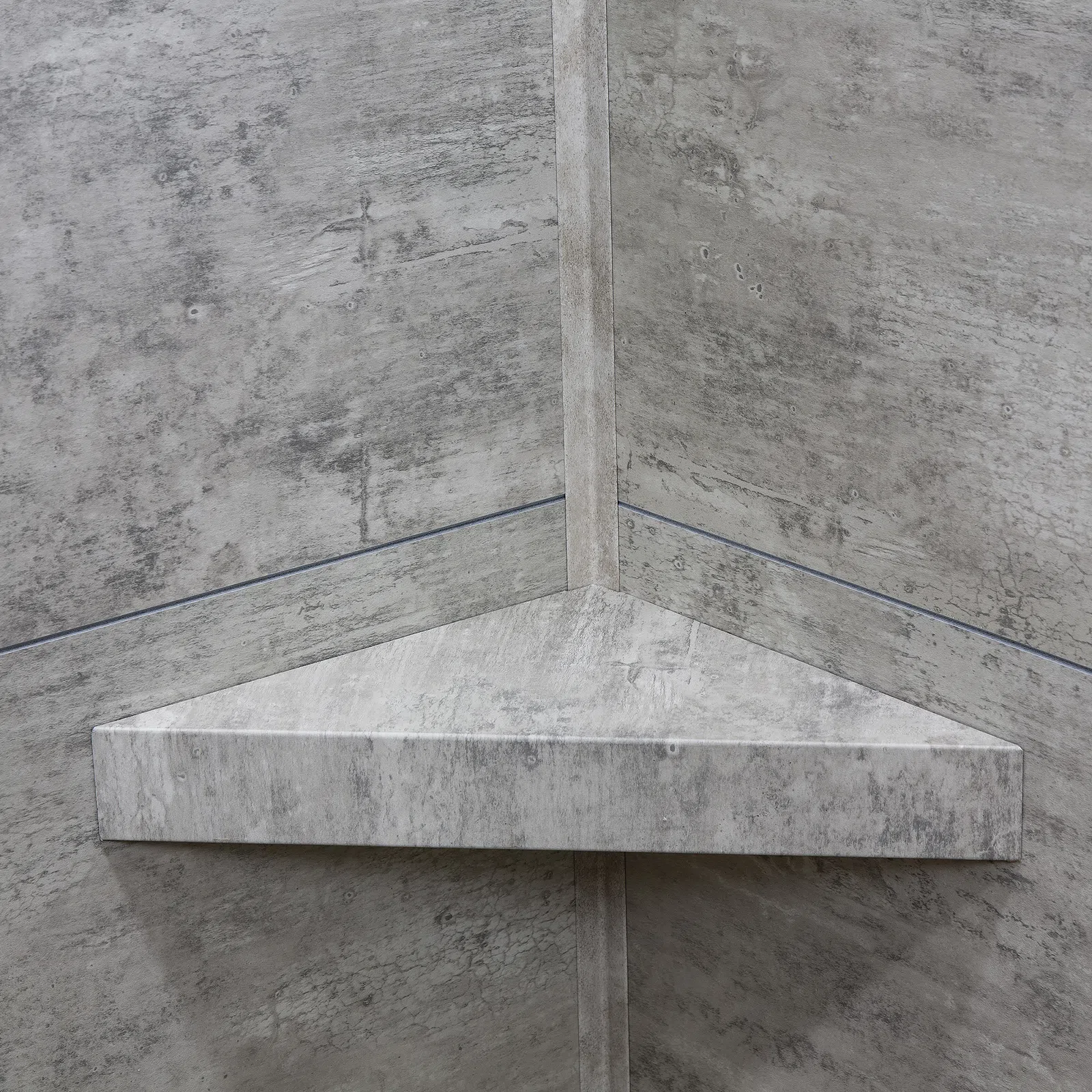 Triangular concrete corner shelf mounted on textured concrete walls with subtle cracks and weathering.
